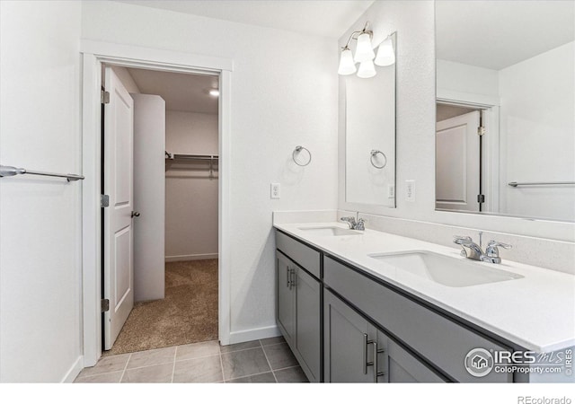 bathroom with a sink, a walk in closet, baseboards, and double vanity