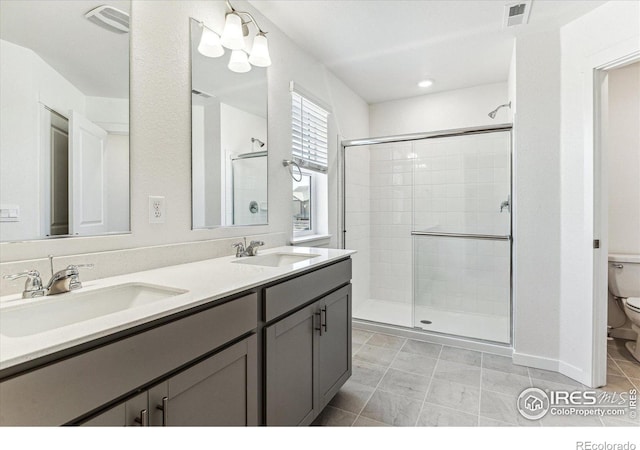 bathroom featuring visible vents, a shower stall, toilet, and a sink