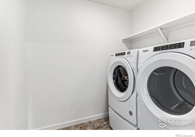 clothes washing area with washer and dryer, laundry area, and baseboards