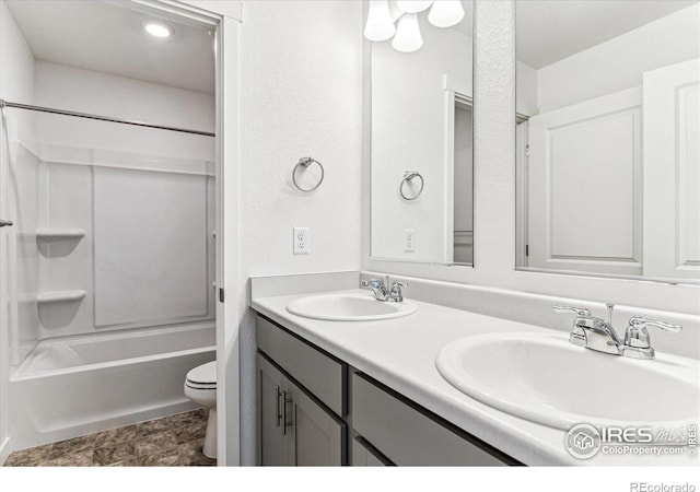 bathroom with double vanity, washtub / shower combination, toilet, and a sink