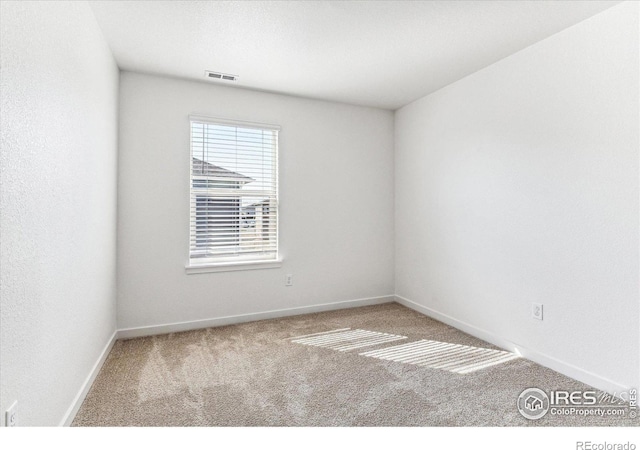 empty room featuring visible vents, baseboards, and carpet