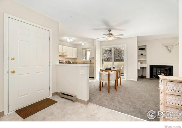 kitchen featuring white cabinetry, a baseboard radiator, ceiling fan, light carpet, and stainless steel dishwasher