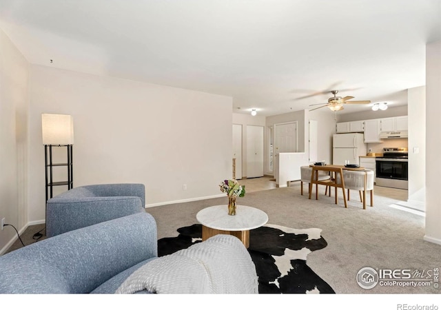 living area featuring light colored carpet, baseboards, and ceiling fan