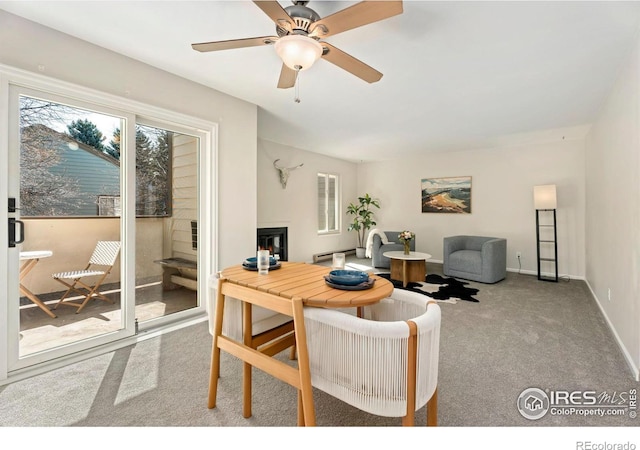 carpeted living room with a glass covered fireplace, baseboards, and a ceiling fan