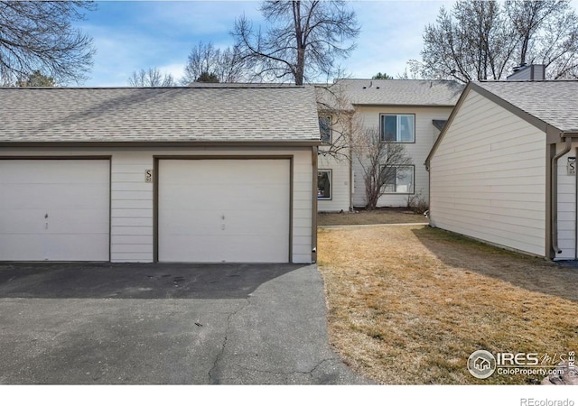 multi unit property featuring a garage and roof with shingles