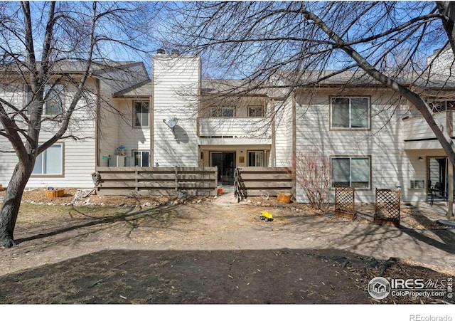 view of front of home featuring a balcony, a fenced front yard, and a chimney