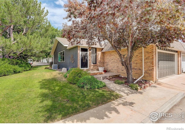 view of front of property with a front yard, cooling unit, driveway, a garage, and brick siding