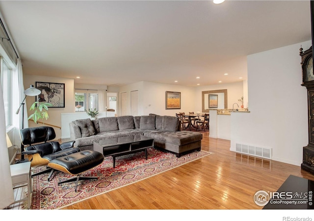 living room with recessed lighting, visible vents, and wood finished floors