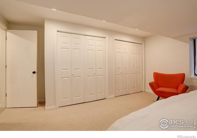 bedroom with two closets, baseboards, and carpet