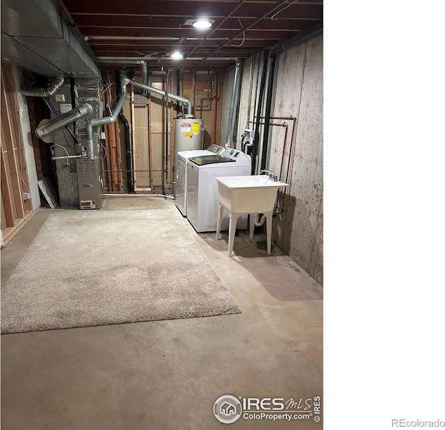 unfinished basement featuring a sink, heating unit, and washer and clothes dryer