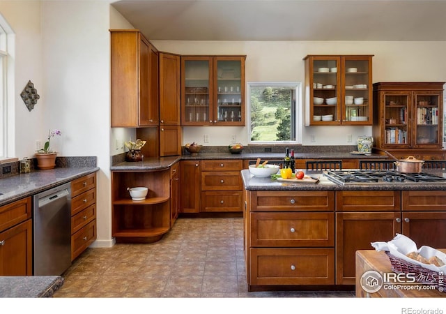 kitchen with dark countertops, glass insert cabinets, brown cabinets, and stainless steel appliances