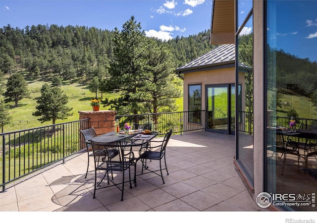 view of patio with outdoor dining area and a wooded view