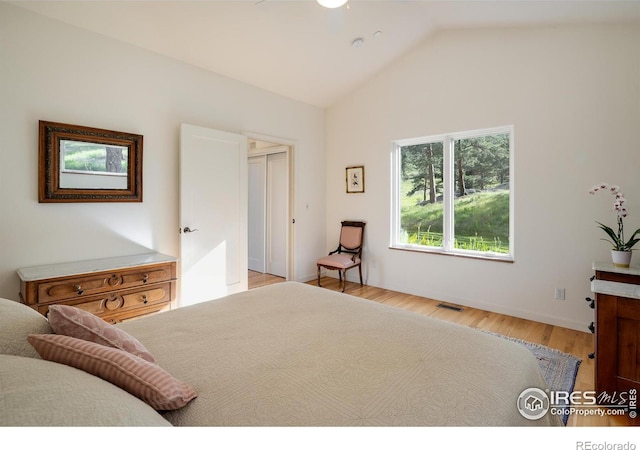 bedroom featuring visible vents, light wood-style floors, and vaulted ceiling