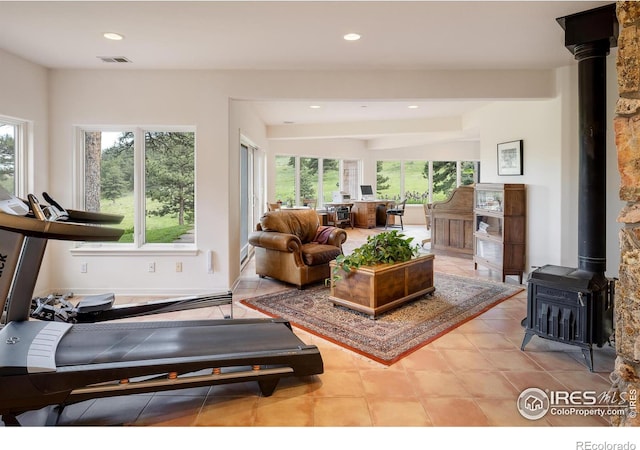 tiled living area with recessed lighting, visible vents, beam ceiling, and a wood stove