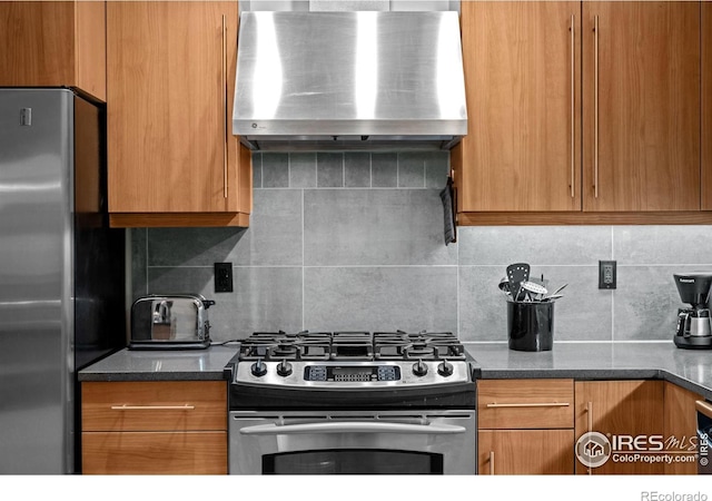 kitchen with brown cabinets, tasteful backsplash, appliances with stainless steel finishes, and wall chimney exhaust hood