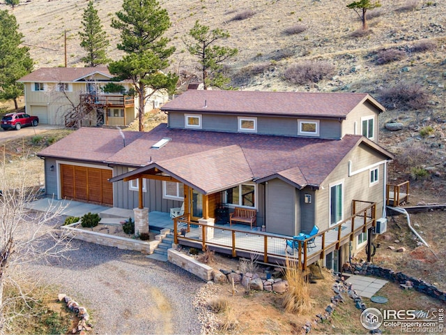 view of front of property with an attached garage, a chimney, a shingled roof, dirt driveway, and board and batten siding