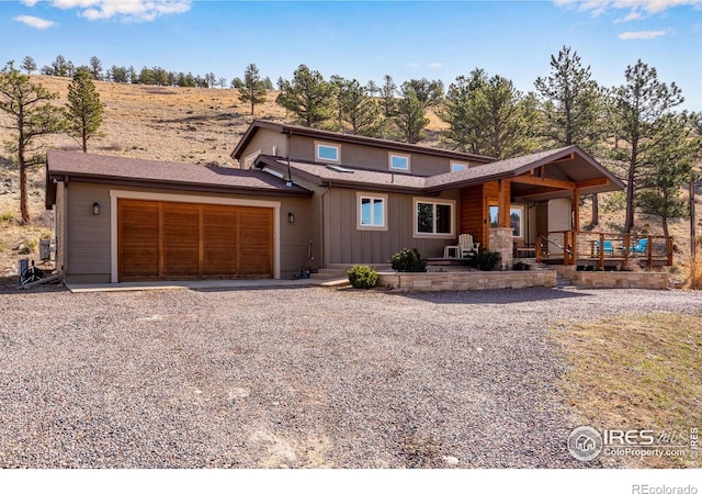 rustic home featuring board and batten siding, a shingled roof, gravel driveway, and a garage