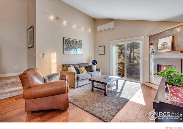 living room featuring high vaulted ceiling, wood finished floors, a fireplace, and a wall unit AC