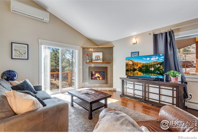 living area with a wall mounted air conditioner, vaulted ceiling, a tile fireplace, wood finished floors, and a baseboard radiator