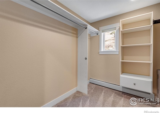 spacious closet featuring a baseboard heating unit and carpet floors