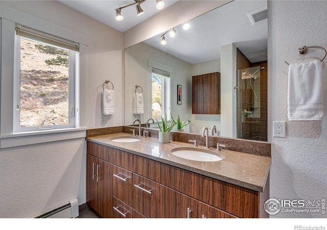 bathroom with visible vents, a baseboard radiator, a tile shower, and a sink