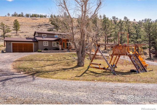 view of front of home with an attached garage, driveway, a playground, and board and batten siding