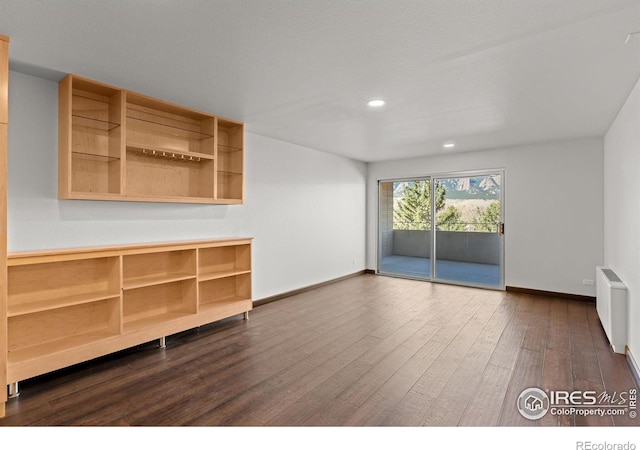 unfurnished living room featuring recessed lighting, radiator, baseboards, and dark wood-style flooring