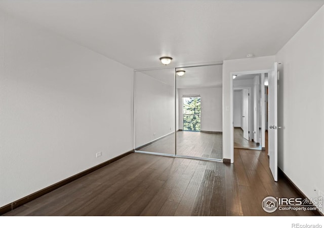 unfurnished bedroom with a closet, baseboards, and hardwood / wood-style flooring