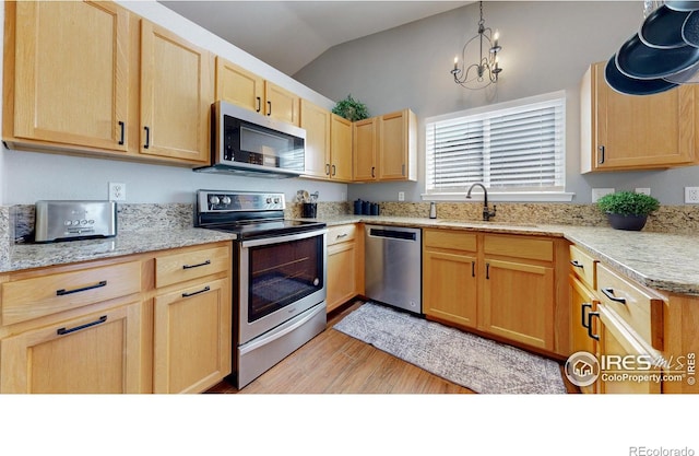 kitchen with vaulted ceiling, light brown cabinets, stainless steel appliances, and a sink