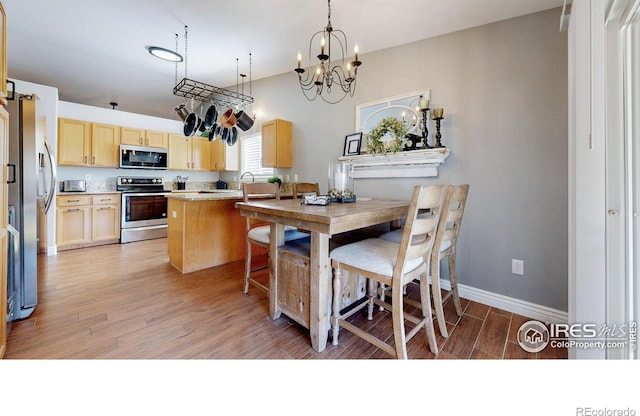 kitchen featuring light brown cabinets, light wood-style floors, appliances with stainless steel finishes, light countertops, and baseboards