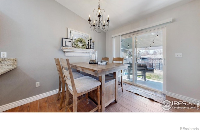 dining room with a notable chandelier, baseboards, and wood finished floors