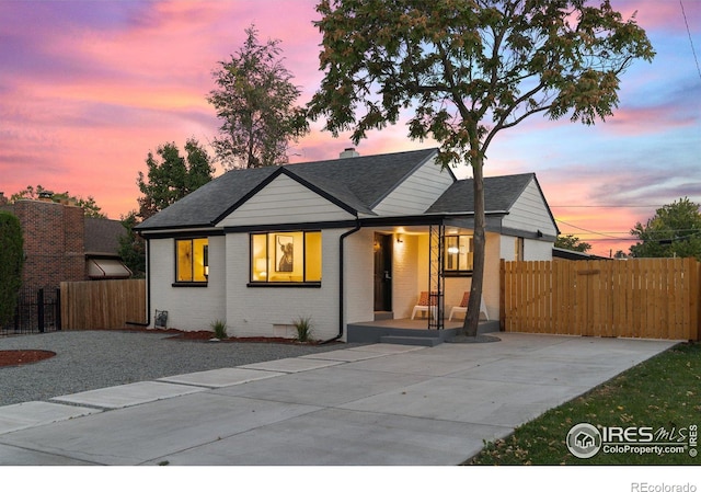 view of front of home featuring a porch, fence, a shingled roof, crawl space, and brick siding