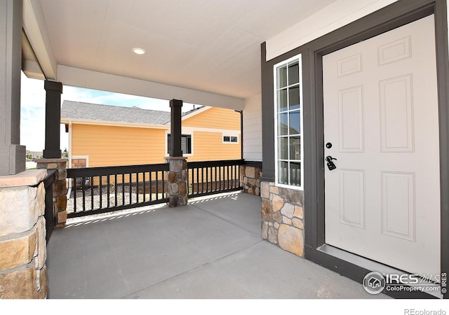 doorway to property featuring covered porch and stone siding