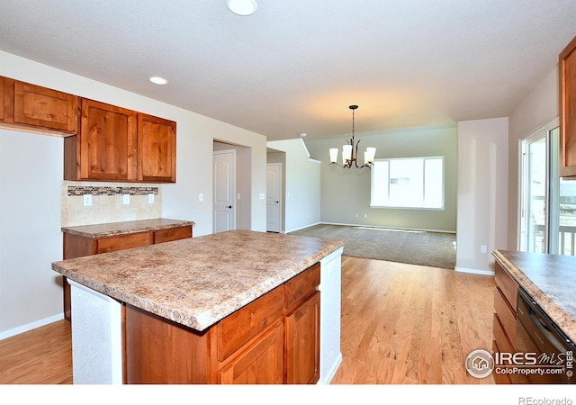 kitchen with tasteful backsplash, light wood finished floors, decorative light fixtures, brown cabinets, and an inviting chandelier