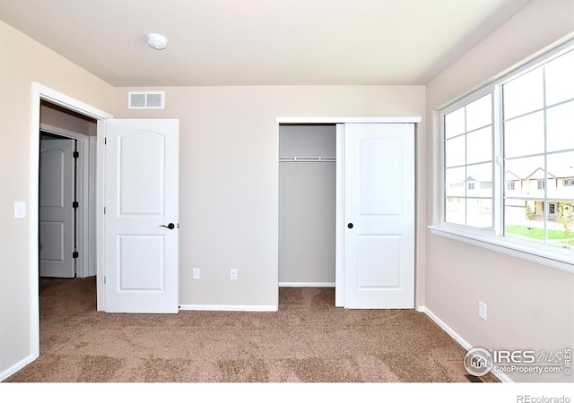 unfurnished bedroom with baseboards, visible vents, carpet floors, and a closet