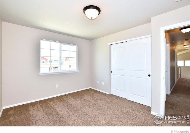 unfurnished bedroom with a closet, baseboards, and carpet