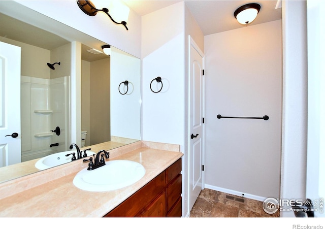 full bathroom featuring vanity, washtub / shower combination, baseboards, stone finish floor, and toilet