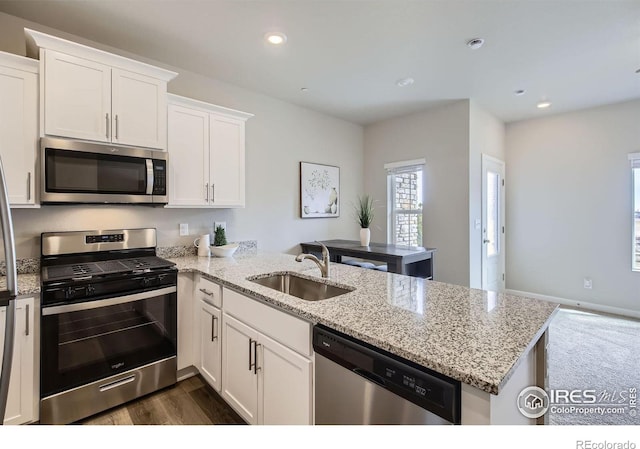 kitchen featuring a peninsula, recessed lighting, a sink, stainless steel appliances, and white cabinetry