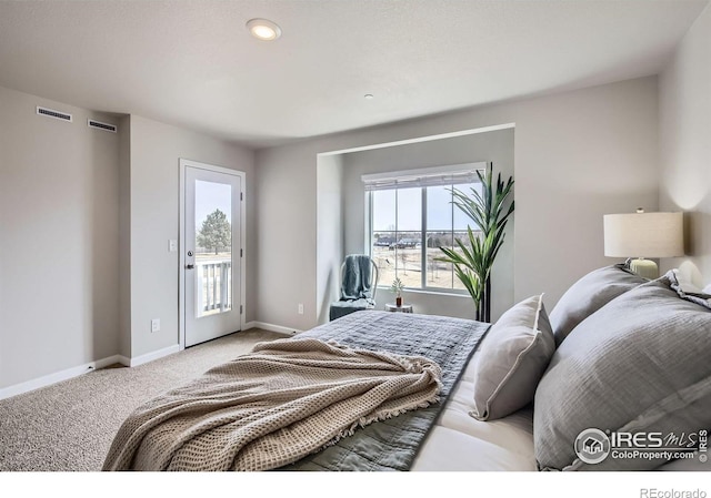 carpeted bedroom with visible vents, baseboards, and access to outside