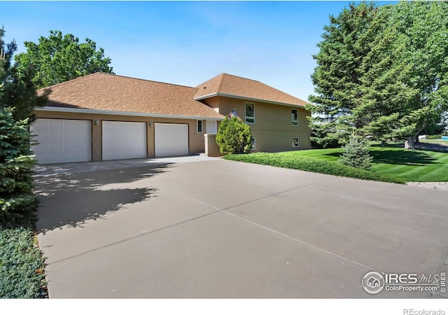 view of front of property with a front lawn, roof with shingles, stucco siding, a garage, and driveway