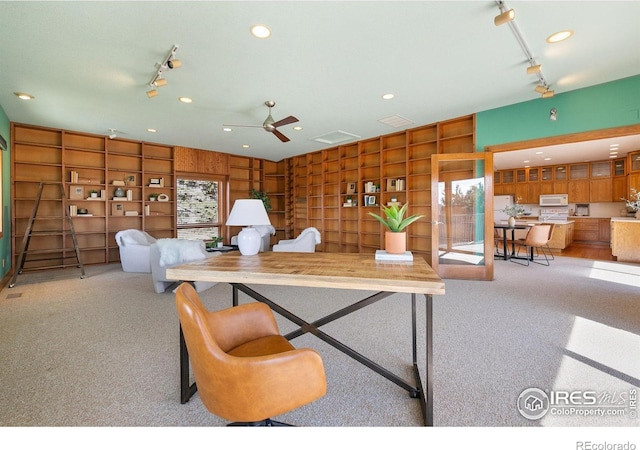 carpeted living room featuring recessed lighting, built in shelves, and rail lighting