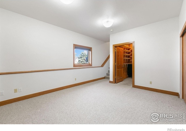 unfurnished bedroom featuring a closet, baseboards, a walk in closet, and carpet flooring