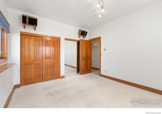 unfurnished bedroom featuring track lighting, baseboards, and carpet