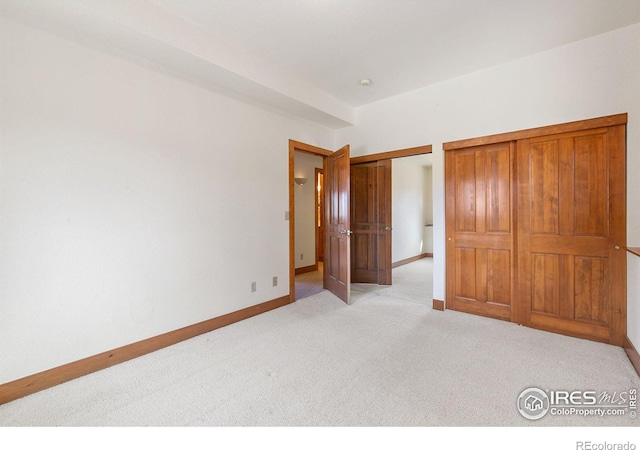 unfurnished bedroom featuring baseboards and light carpet