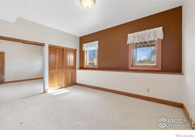 unfurnished bedroom featuring baseboards, multiple closets, and carpet flooring