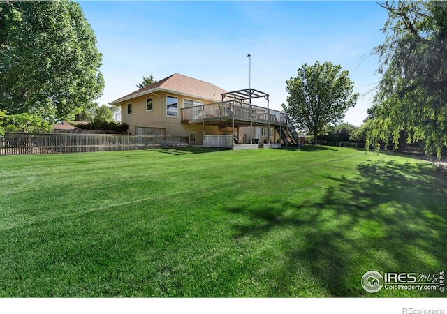 view of yard with a wooden deck, stairs, and fence