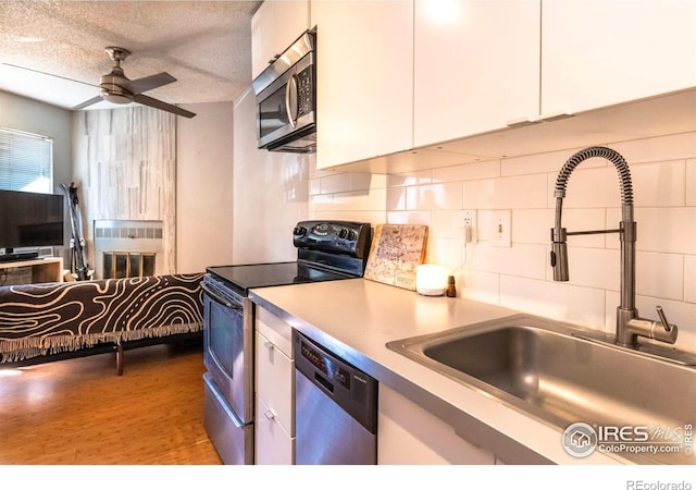 kitchen featuring a sink, stainless steel appliances, white cabinets, and a ceiling fan