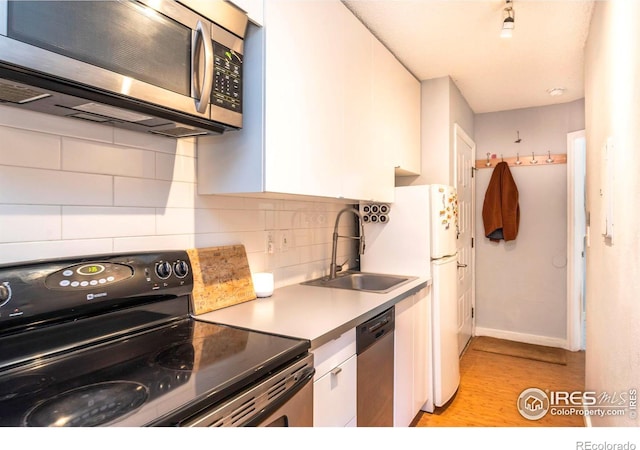 kitchen with a sink, stainless steel appliances, backsplash, and white cabinetry