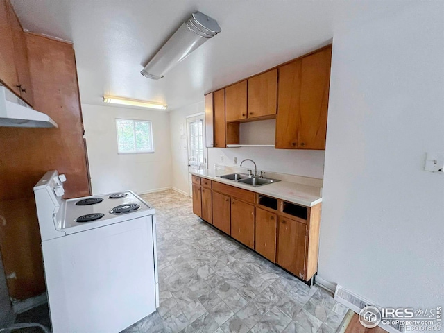 kitchen with a sink, electric range, brown cabinets, and light countertops