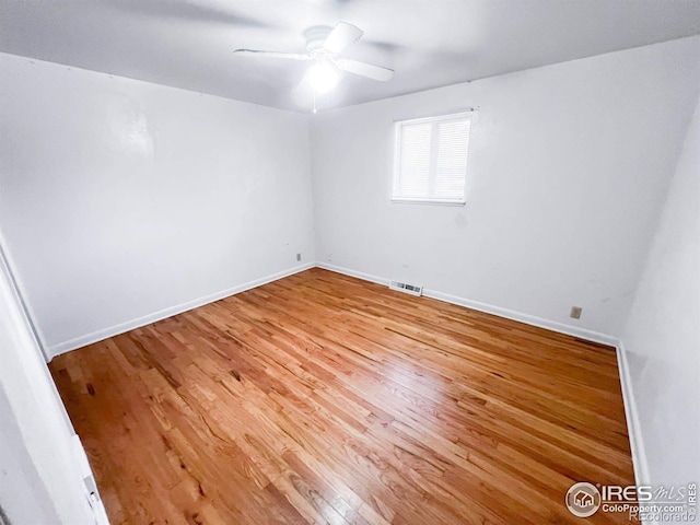 unfurnished room featuring ceiling fan, visible vents, baseboards, and wood finished floors